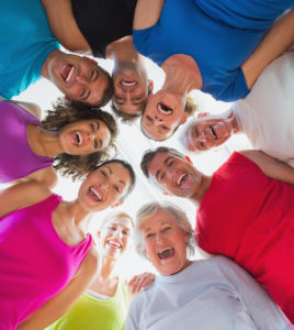 Low angle portrait of cheerful people forming huddle at gym